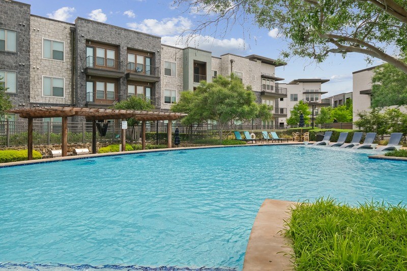 A large swimming pool in front of apartment buildings.