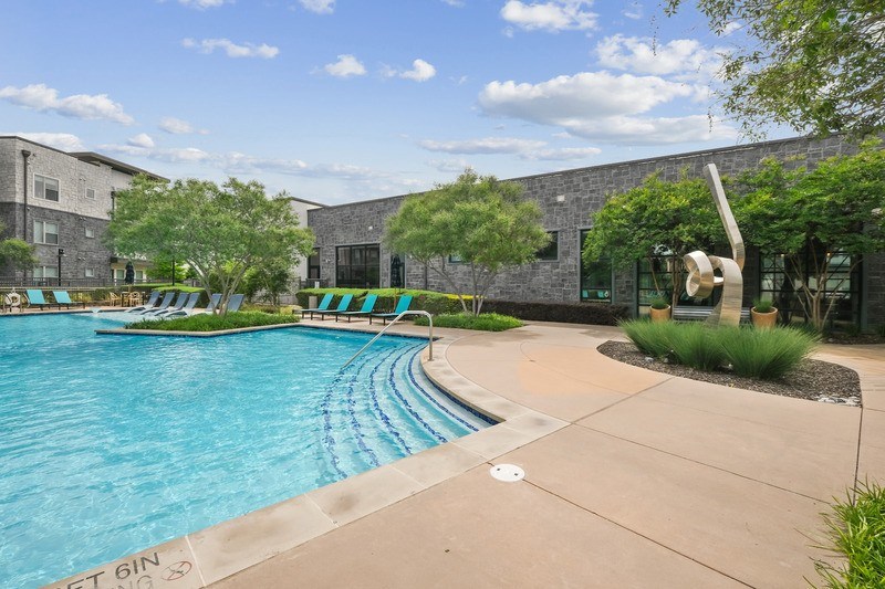 A swimming pool with a slide and a building in the background.