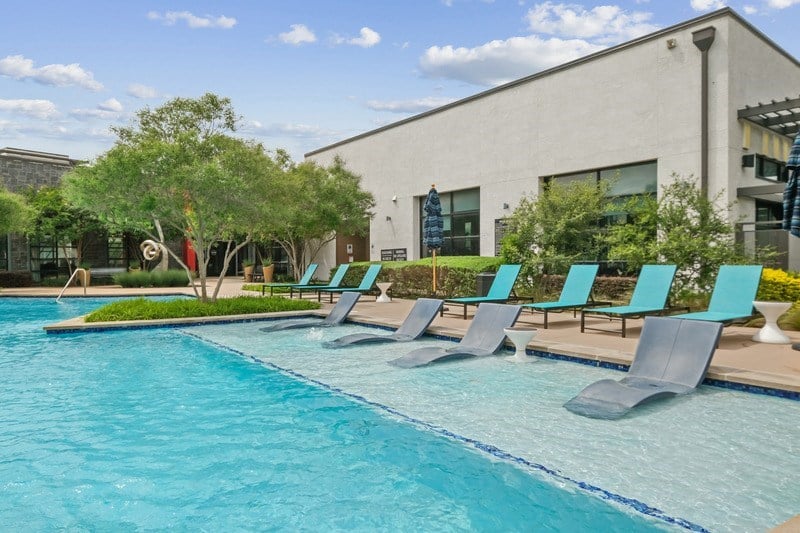 A pool with blue water and chairs around it.