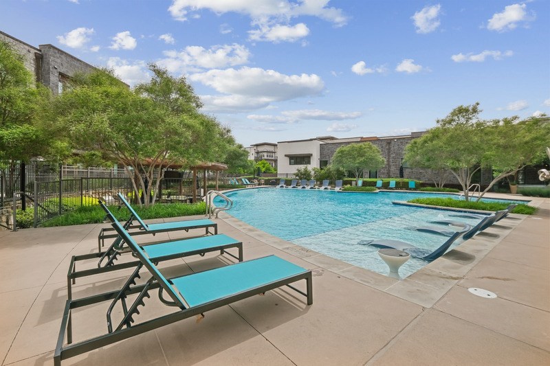 A pool with a bench is surrounded by trees.
