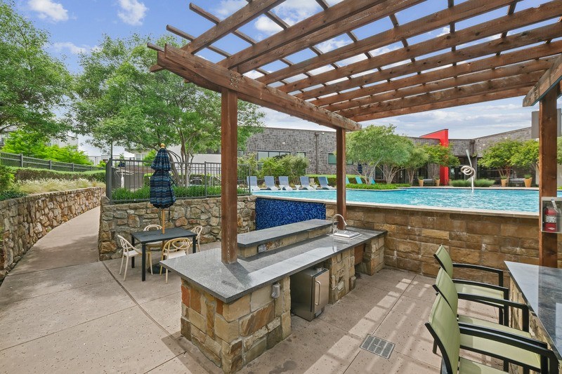 A patio with a table and chairs under a wooden pergola.