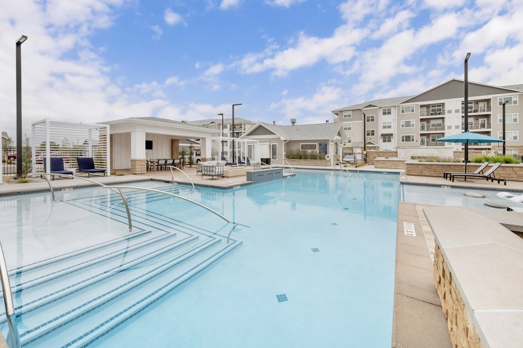 A large outdoor swimming pool an apartment building in the background.