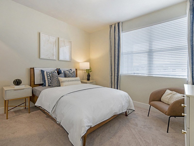 a bedroom with a bed and a chair and a window