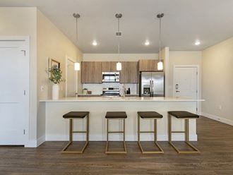 a kitchen with a bar and three stools in front of a counter top