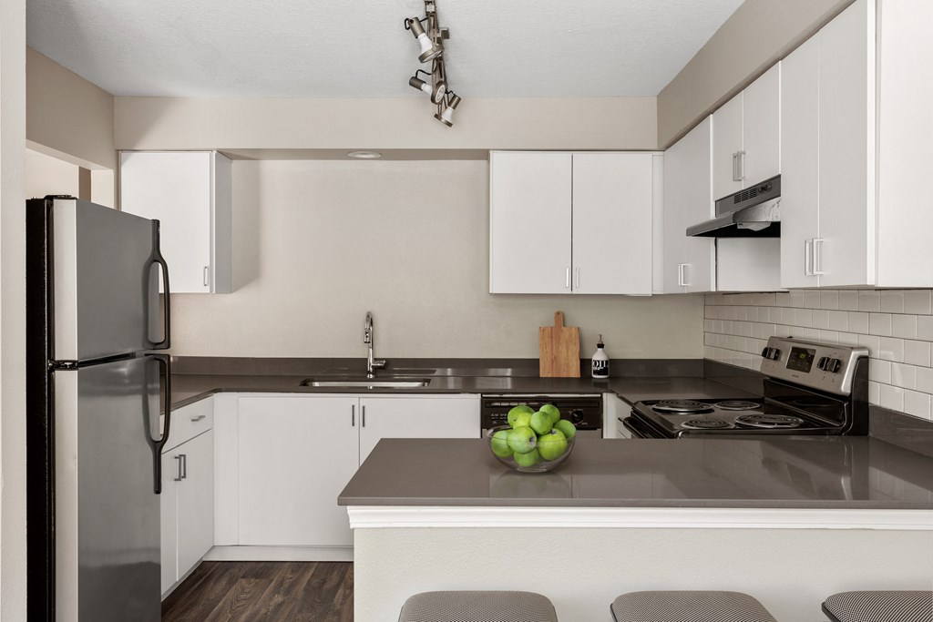 a kitchen with white cabinets and a counter top with a bowl of fruit