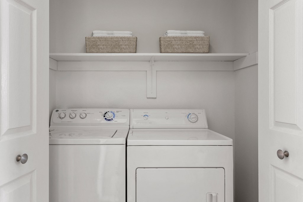 a white washer and dryer in a laundry room with two baskets on top
