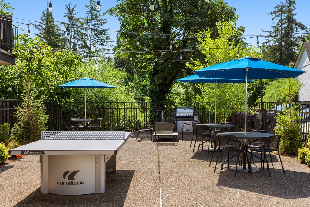 a patio with tables chairs and umbrellas and a grill