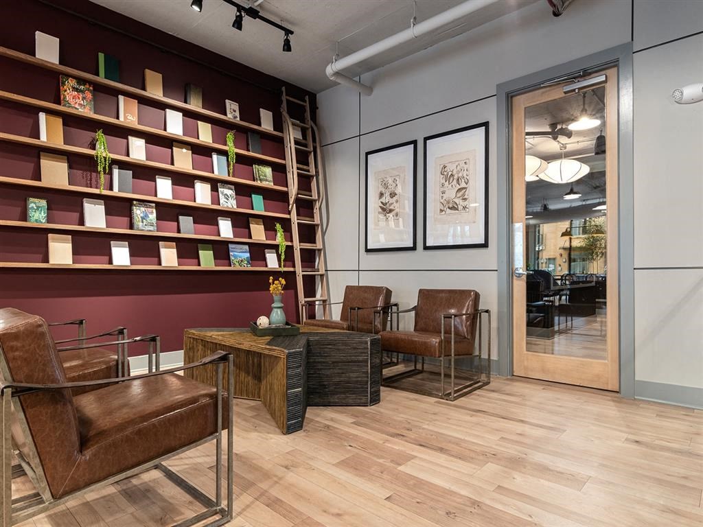 A room with a brown leather chair and a wooden table with a vase on it.