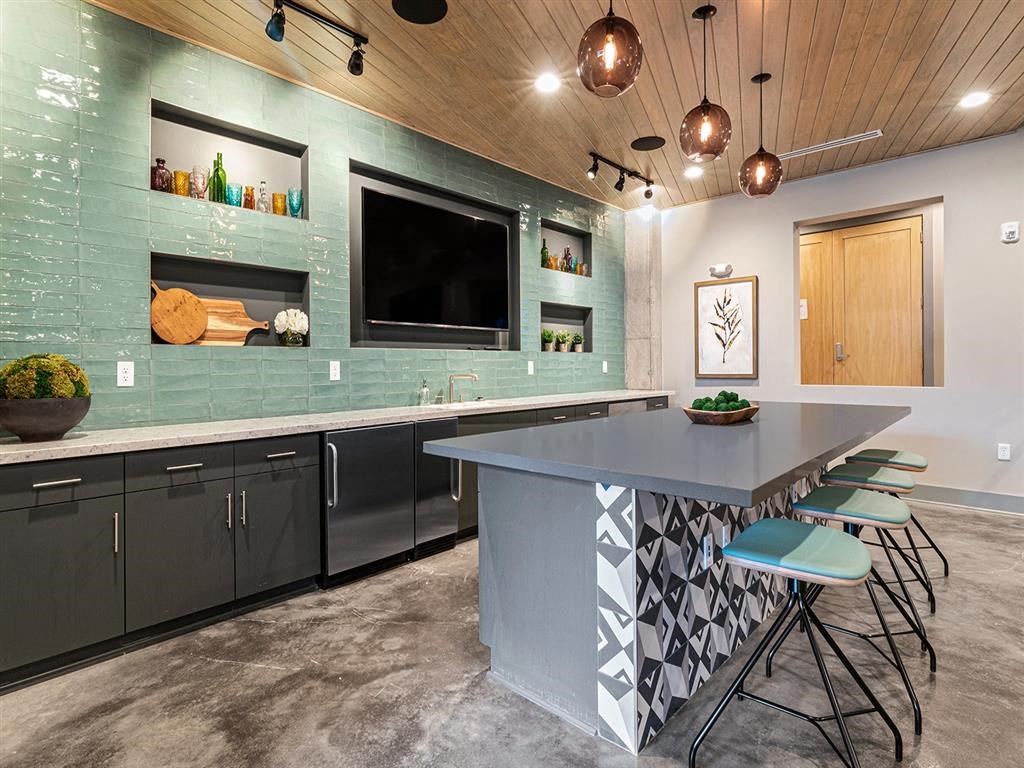 A kitchen with a grey island and a wooden ceiling.