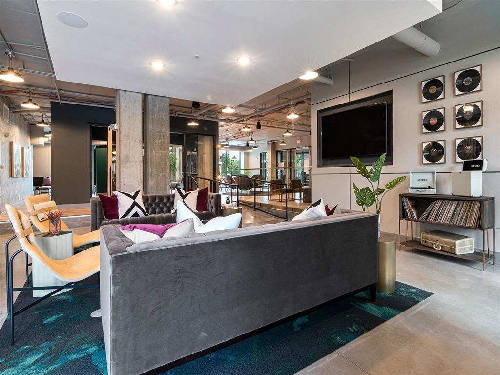 A modern living room with a grey couch and a television on the wall.