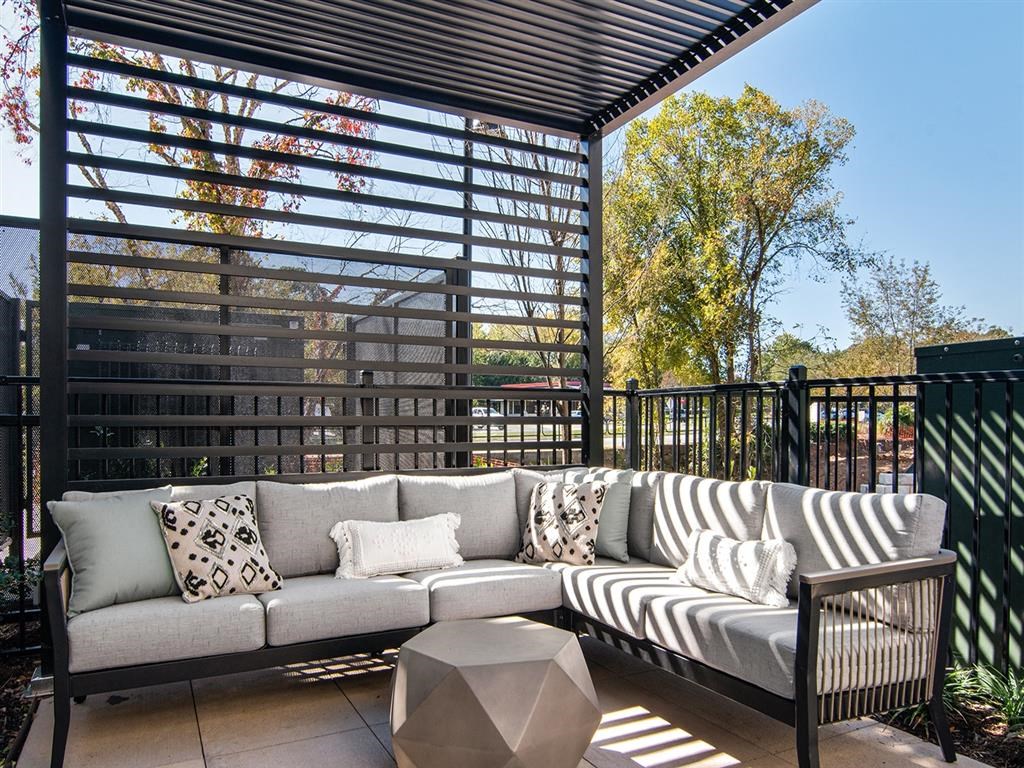 A patio with a grey sofa and a black metal fence.