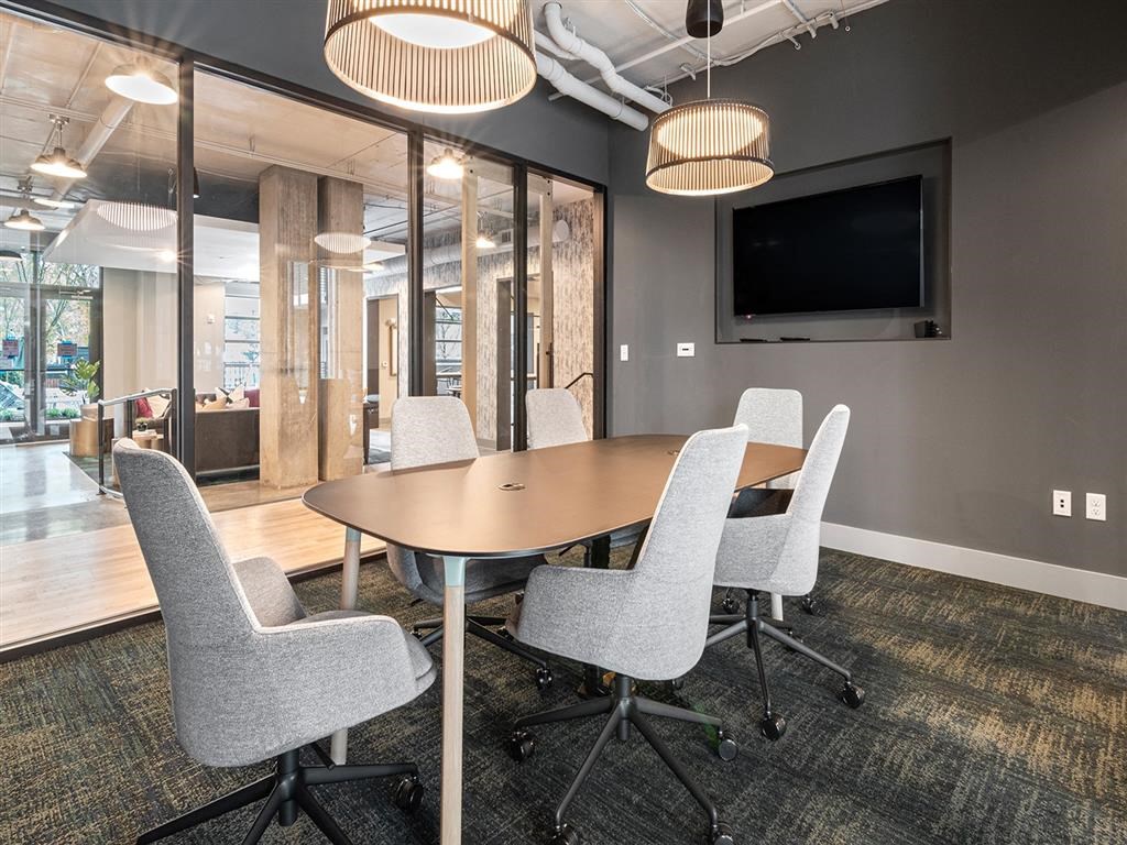 A conference room with a table, chairs, and a television mounted on the wall.