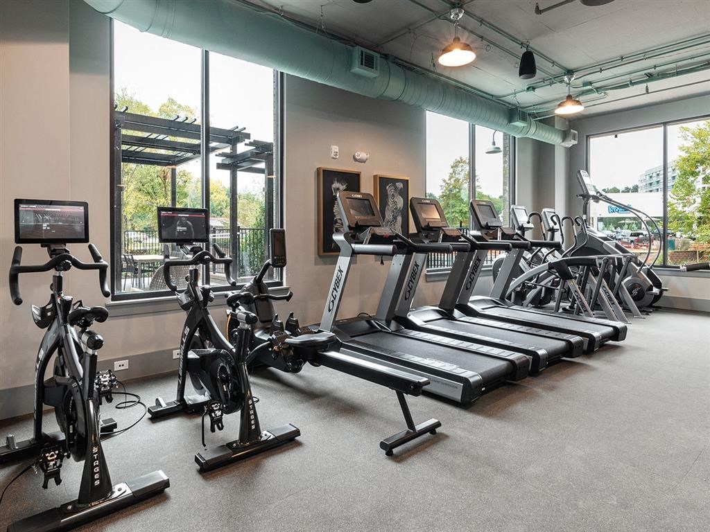 A gym with treadmills, exercise bikes, and a treadmill in the background.