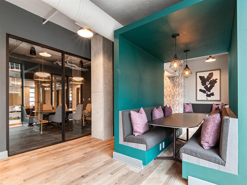 A modern dining area with a round table and grey cushioned bench.