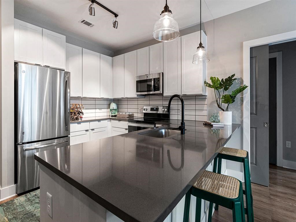 A modern kitchen with a stainless steel refrigerator and a dark countertop.