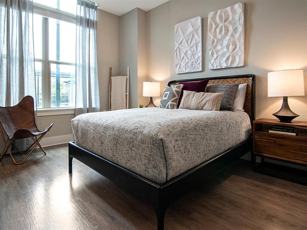 A bedroom with a large bed and a chair by the window.