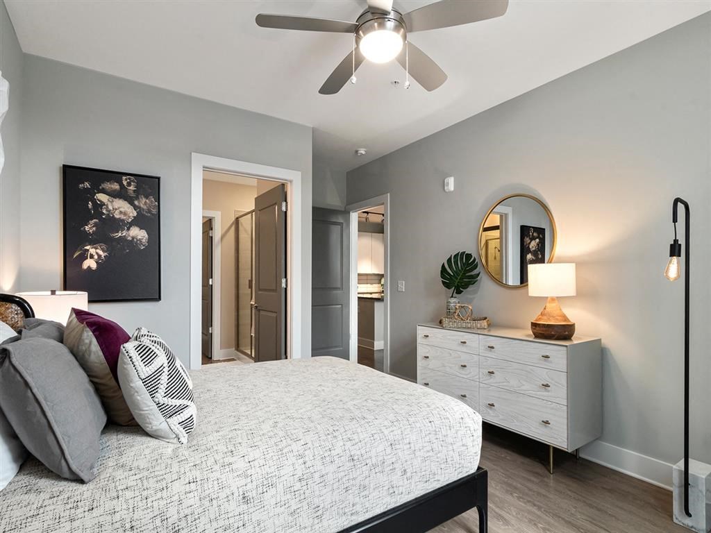 A bedroom with a bed, dresser, mirror, and a ceiling fan.