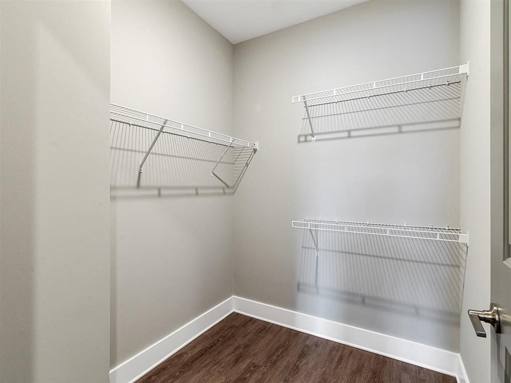 A walk-in closet with shelves and a wooden floor.