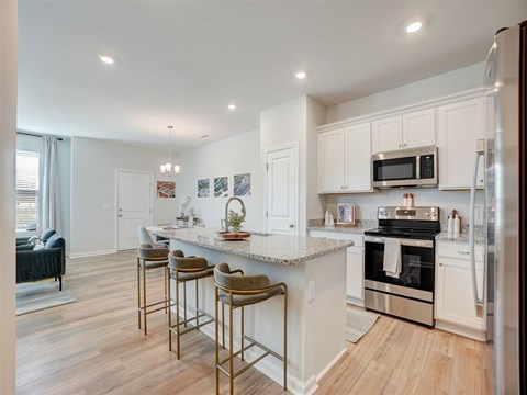 A kitchen with white cabinets and a marble countertop.
