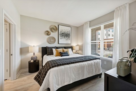 A bedroom with a large bed and a window with blinds.