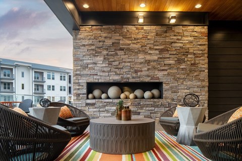 A patio with a stone fireplace and wicker chairs.
