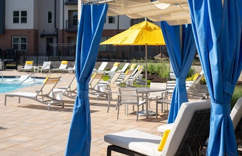 A poolside area with blue umbrellas and yellow umbrellas.