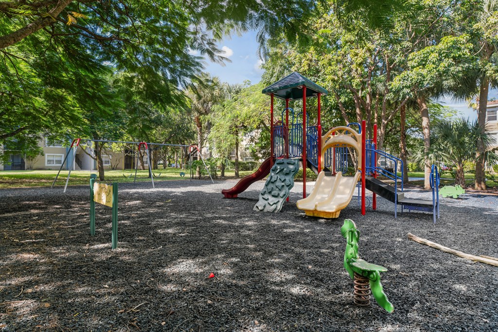 A playground with a green slide and a red and yellow slide.