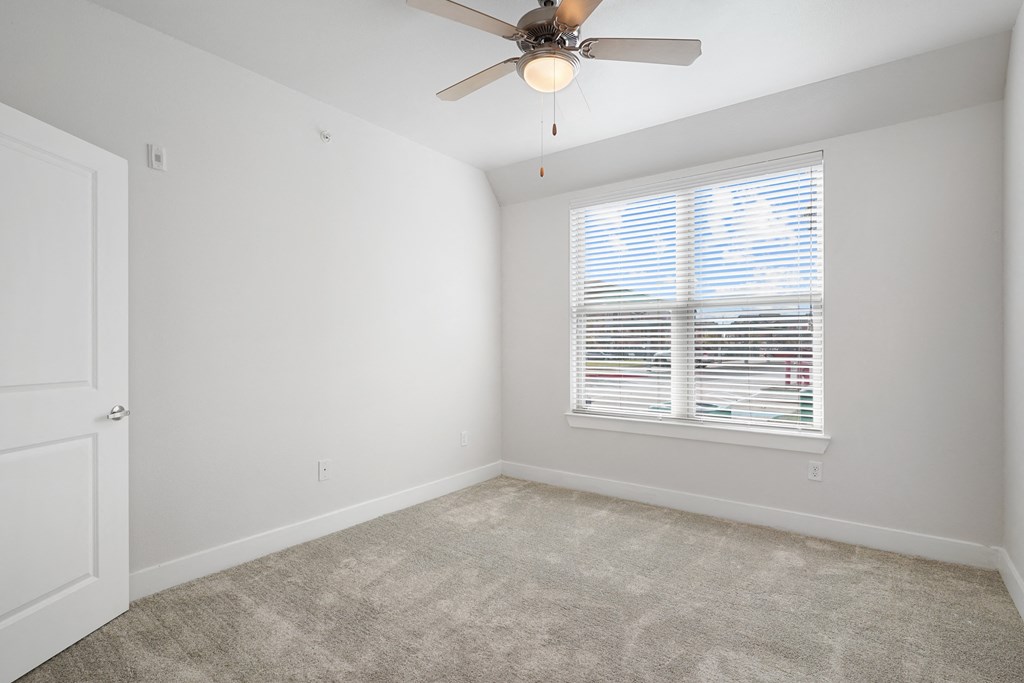 an empty room with a ceiling fan and a window