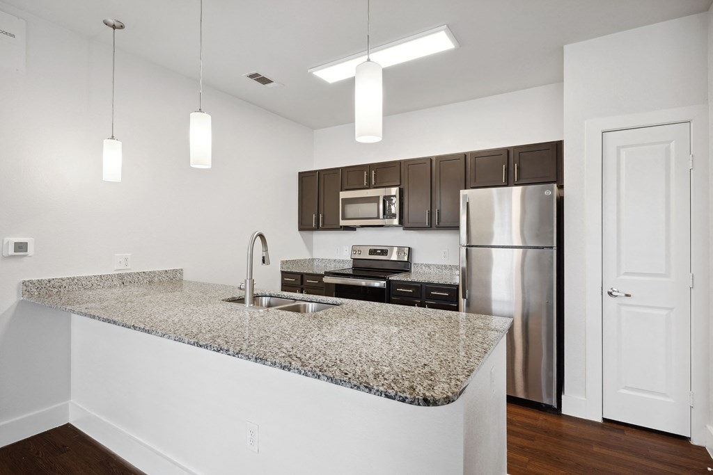 a kitchen with granite counter tops and a stainless steel refrigerator
