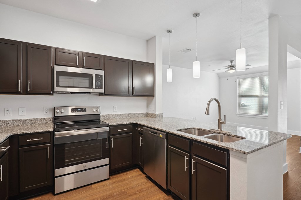 a kitchen with black cabinets and a sink and a microwave