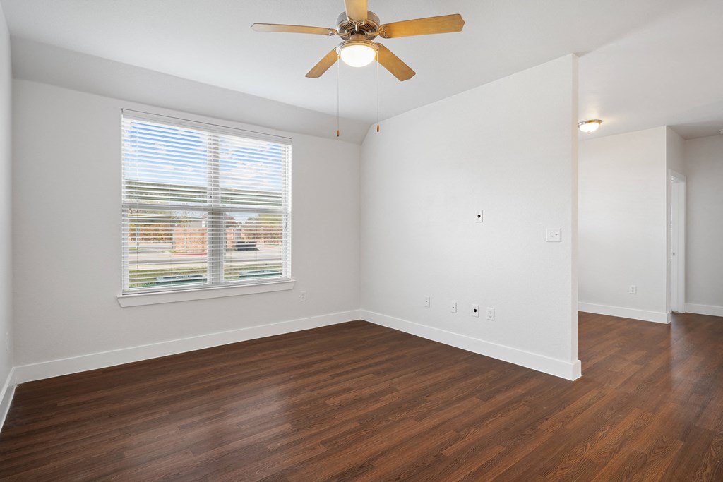 an empty living room with a ceiling fan and a window