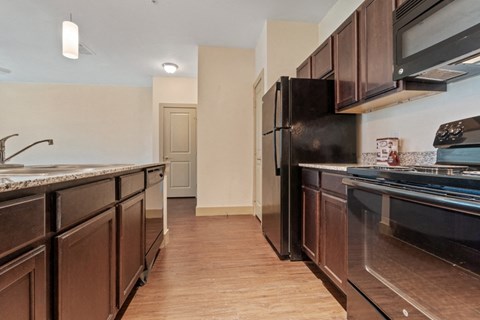 a kitchen with dark wood cabinets and a black refrigerator