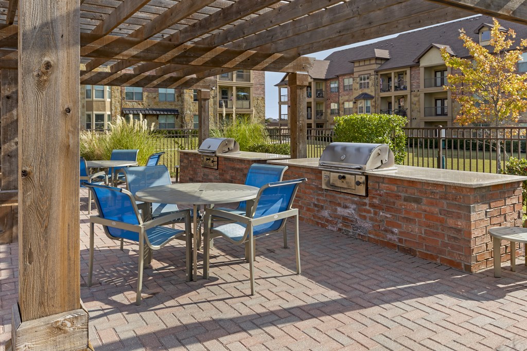 a patio with a barbecue grill and a table with chairs