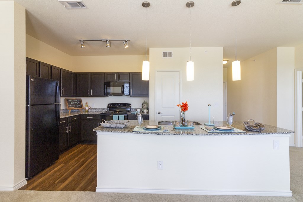 a kitchen with black appliances and a large island with plates of food
