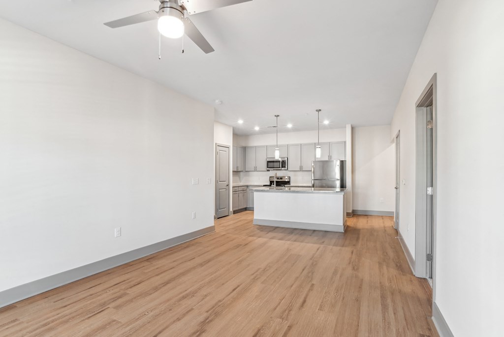 a living room with a kitchen and a ceiling fan