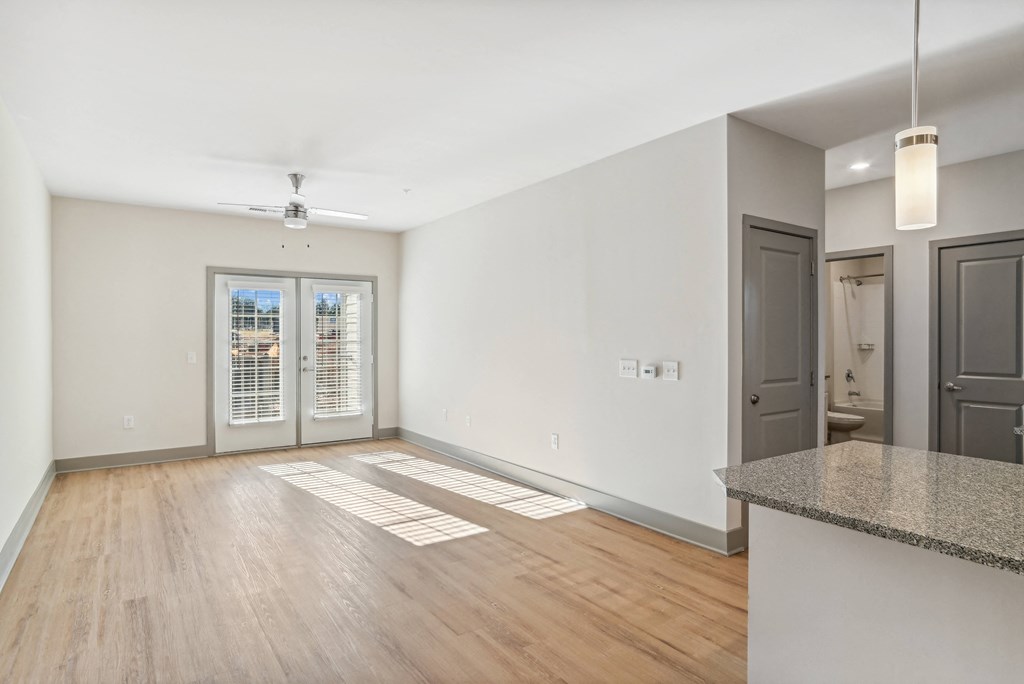 the living room and dining room of an apartment with white walls and wood floors
