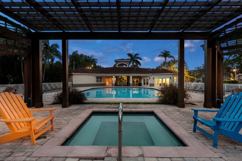 a swimming pool with two chairs and a house in the background