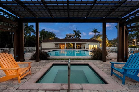 a swimming pool with two chairs and a house in the background