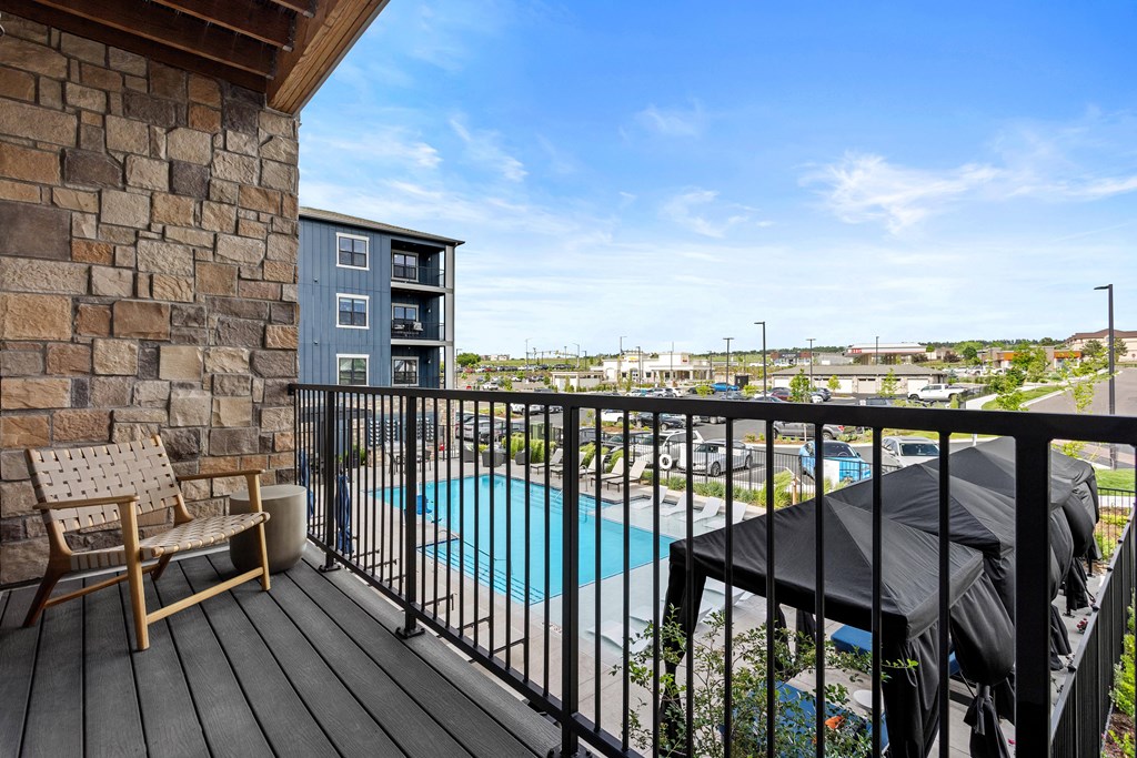 A balcony with a chair and a pool.