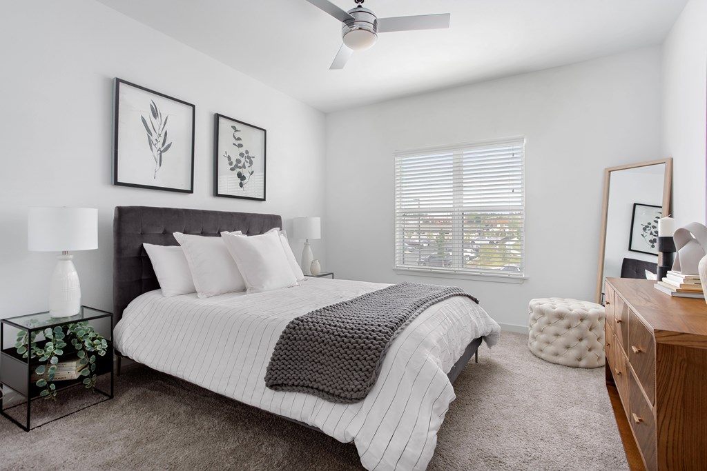 A bedroom with a bed, nightstand, and a ceiling fan.