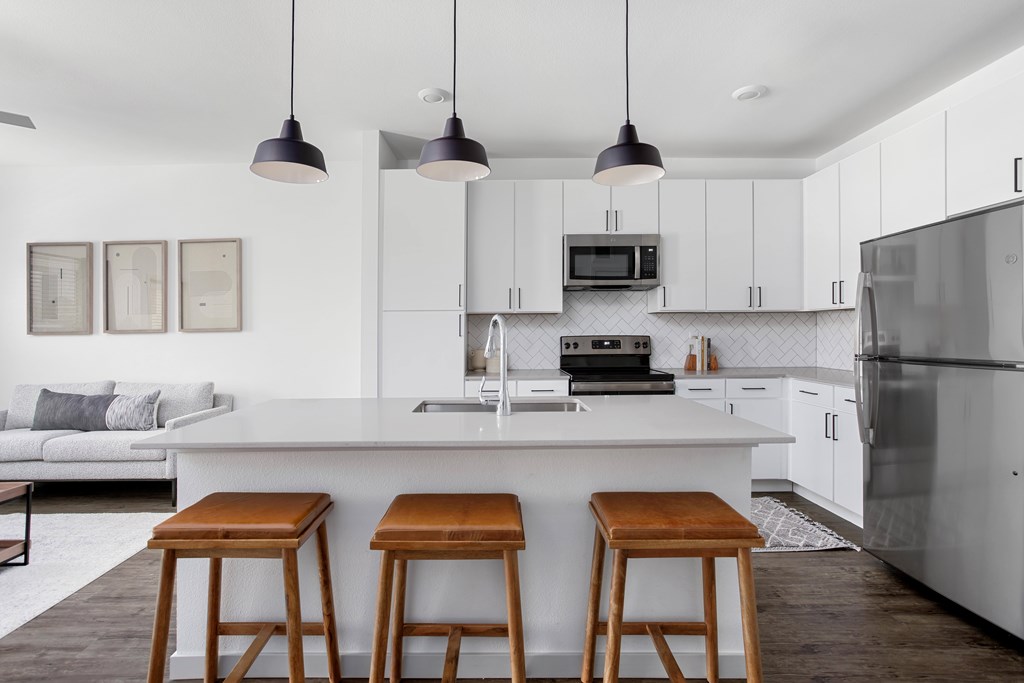 A modern kitchen with a white island and bar stools.