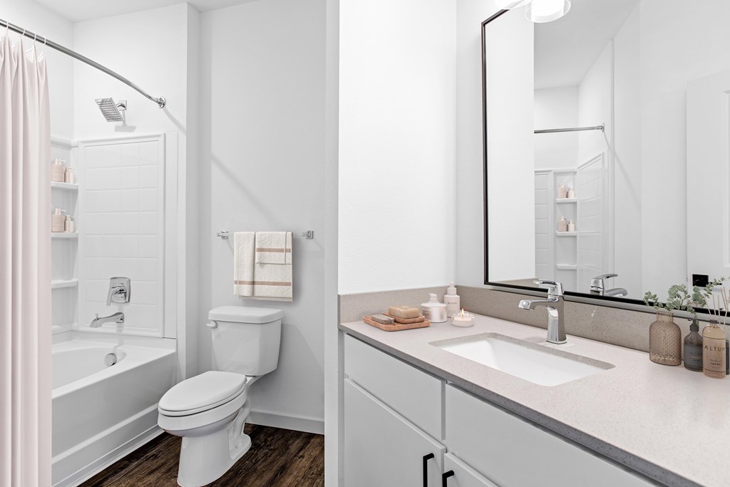 A white bathroom with a toilet, sink, and mirror.