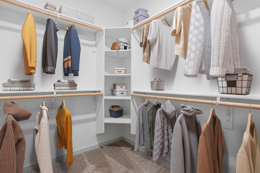 A white closet with clothes hanging and shelves.