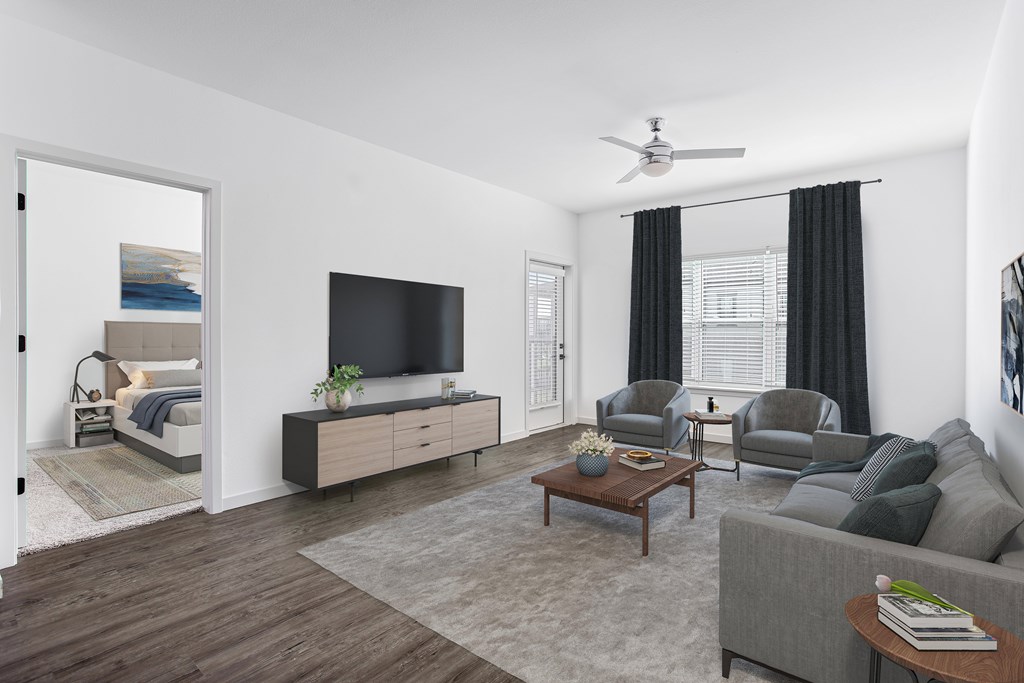 A modern living room with a grey sofa, a wooden coffee table, and a flat-screen TV.