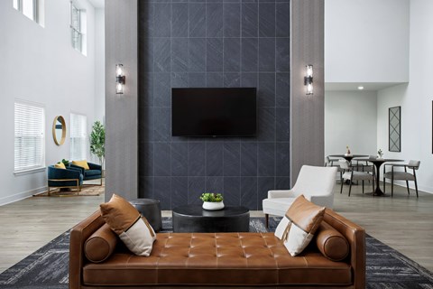 A modern living room with a brown leather sofa and a flat screen TV mounted on the wall.