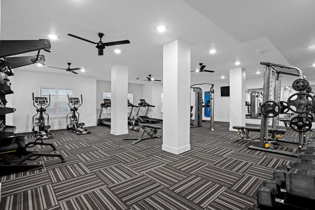 A gym with a variety of equipment including treadmills, weights, and exercise machines.