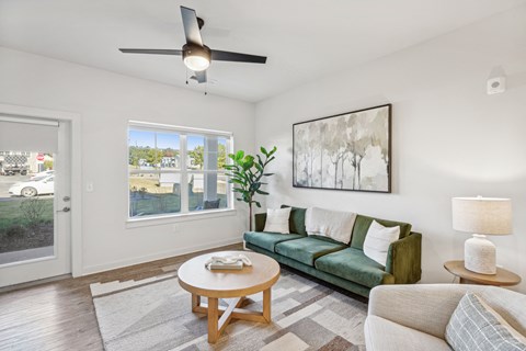 a living room with a green couch and a ceiling fan