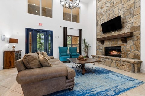 A living room with a brown couch and a stone fireplace.