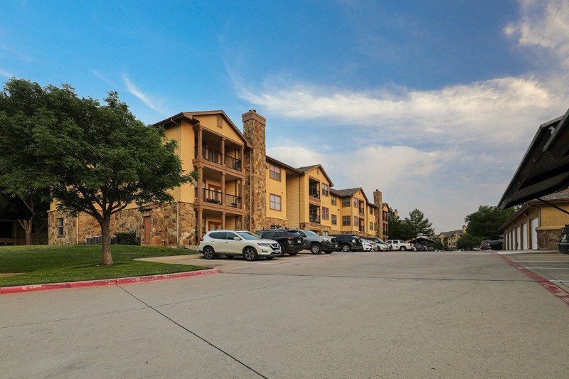 an empty street with cars parked in front of an apartment building