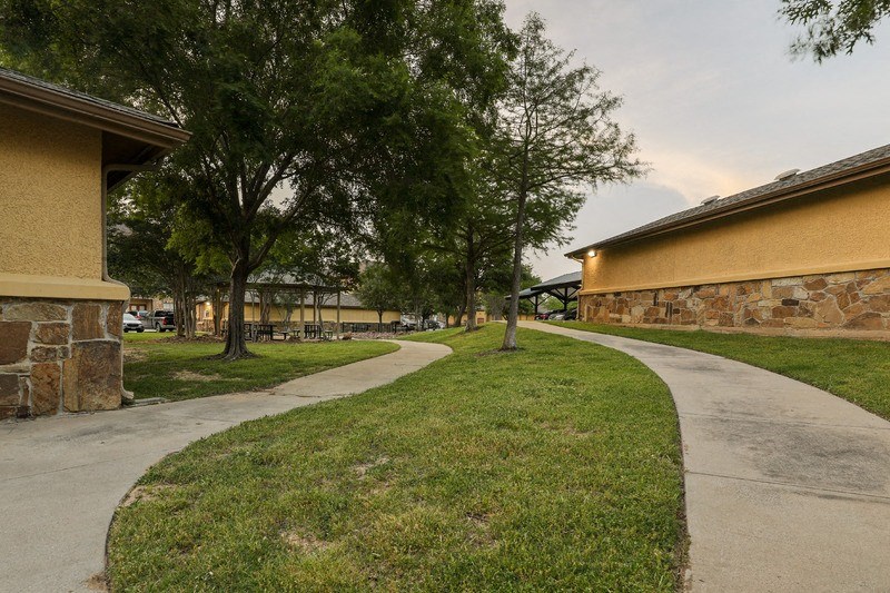a sidewalk in front of a building with trees